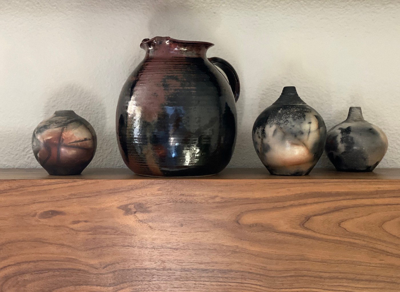 a family of hand-thrown ceramics and Raku on s mantel